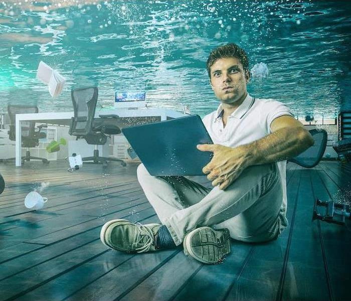 man work sit on the floor with his laptop in flooded office