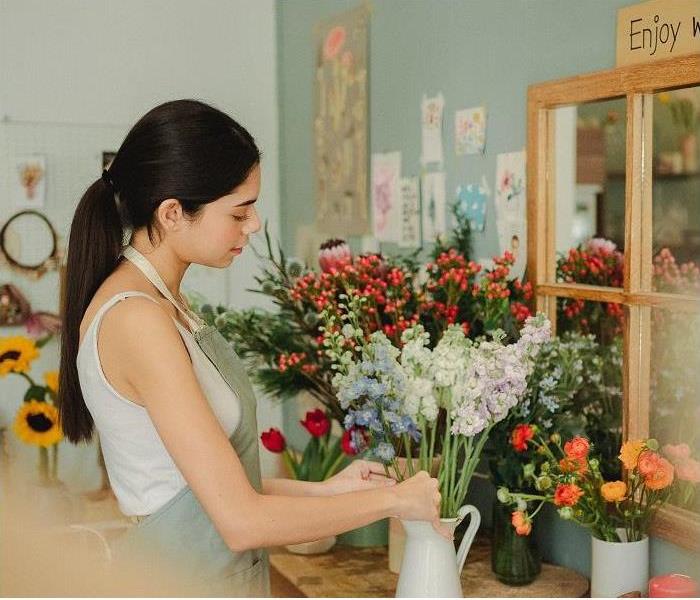 woman arranging flowers in front of mirror in flower shop